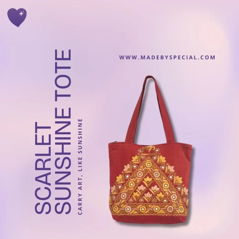 A handcrafted scarlet red tote bag with traditional yellow, orange, and white embroidered patterns forming a triangle. Displayed on a soft pink background with the text “Scarlet Sunshine Tote – Carry art, like sunshine”